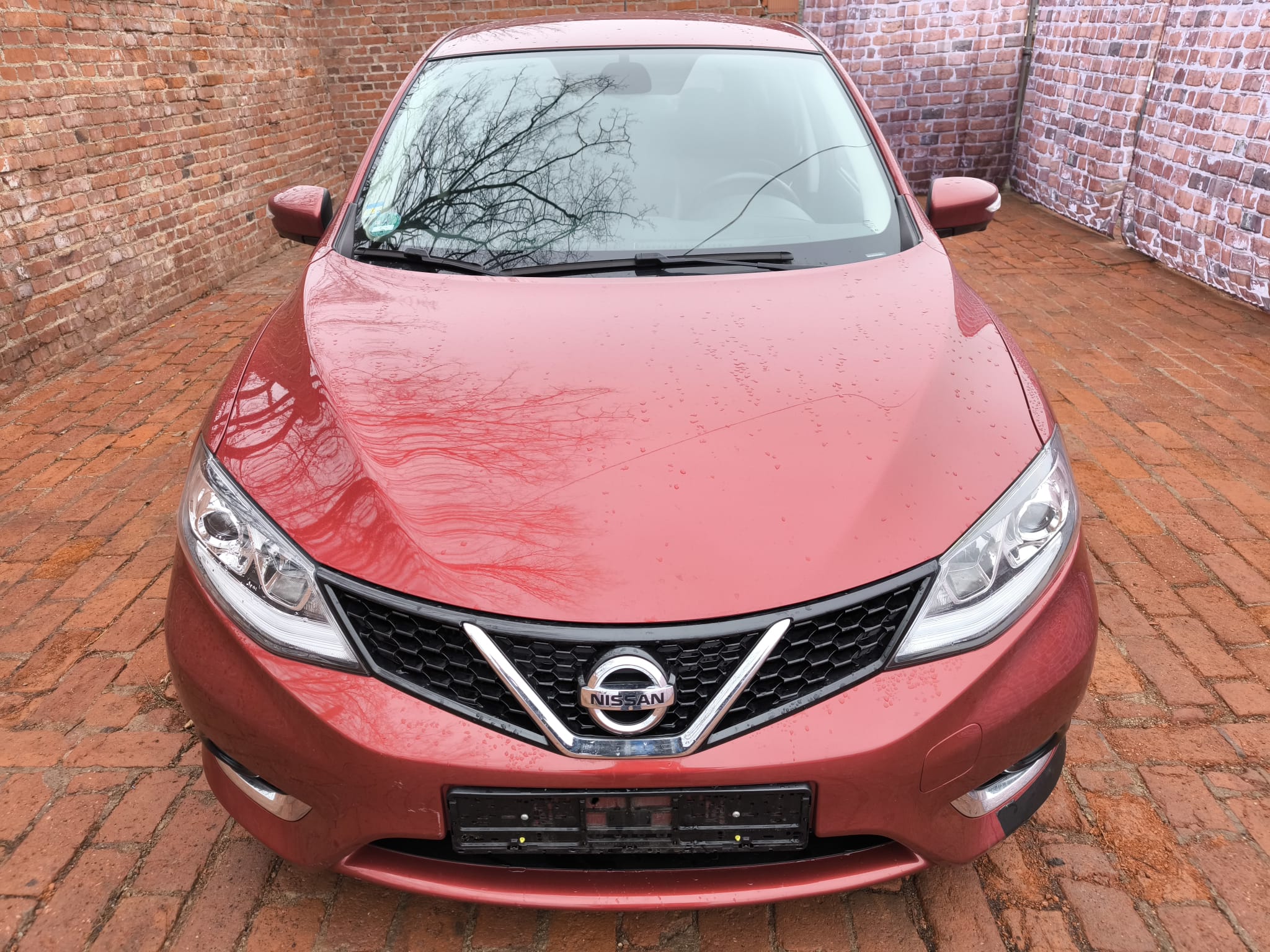 Nissan mit Getriebeschaden in Bremerhaven verkaufen - rote Limousine frontal vor Backsteinmauer