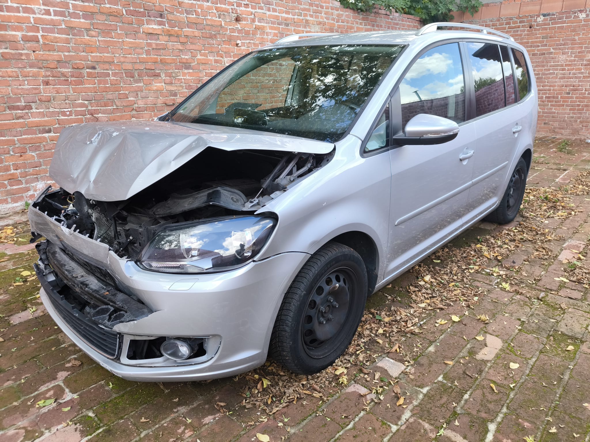 In Bünde verkaufter VW Touran als Unfallwagen mit Frontschaden vor Ziegelmauer