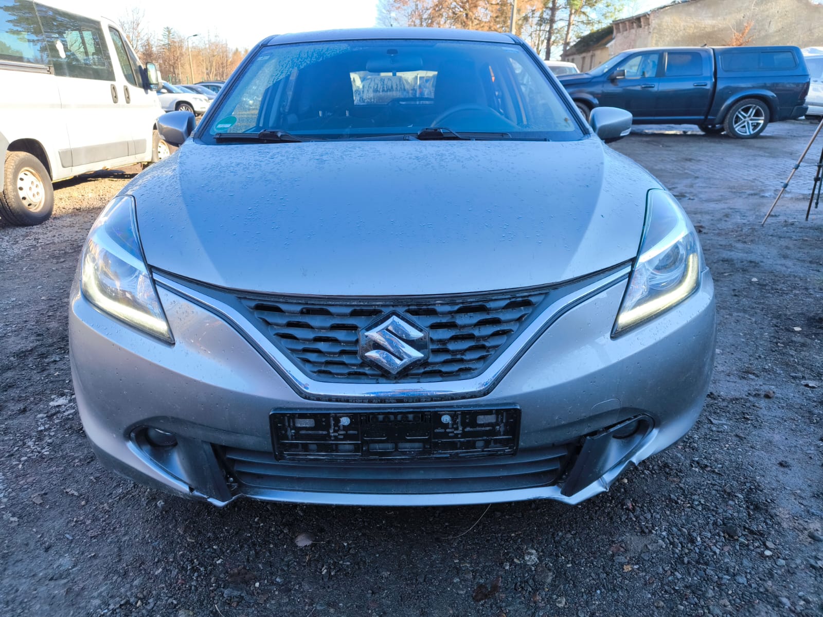 Silberner Suzuki Baleno mit Motorschaden von vorn nach Verkauf in Dresden auf einem Parkplatz