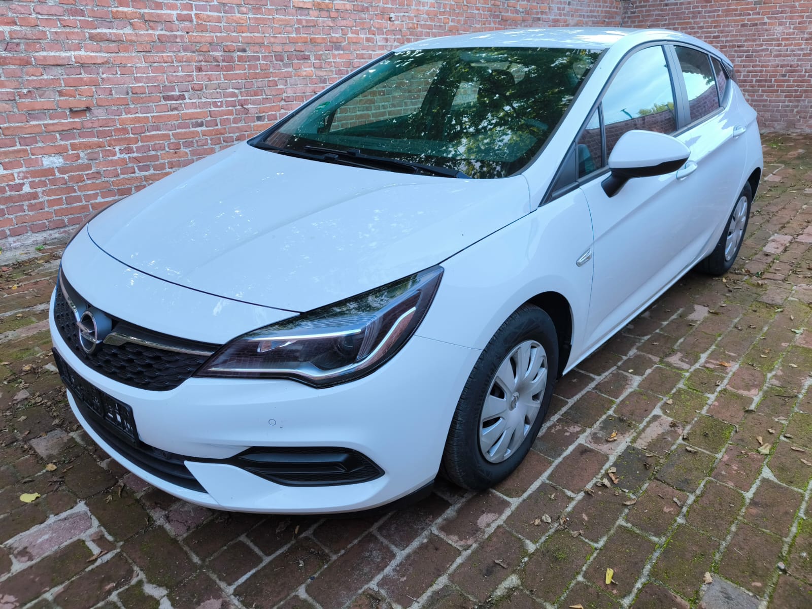 Weißer Opel Astra Kombi nach Verkauf als Schadenfahrzeug in Herten vor Ziegelwand