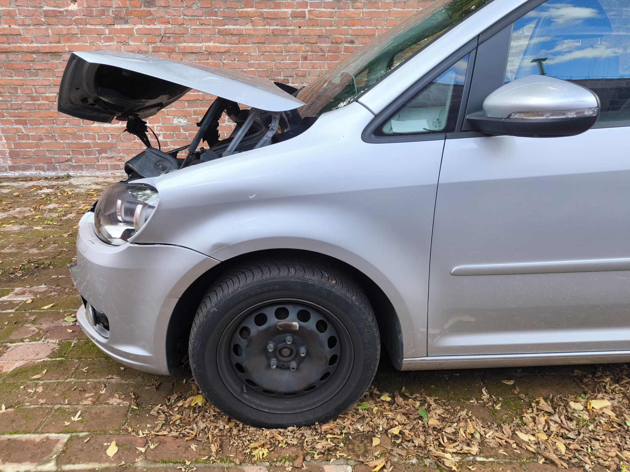 Unfall VW Touran mit geöffnetem und beschädigtem Vorderwagen vor Ziegelwand in Hofheim am Taunus verkaufen