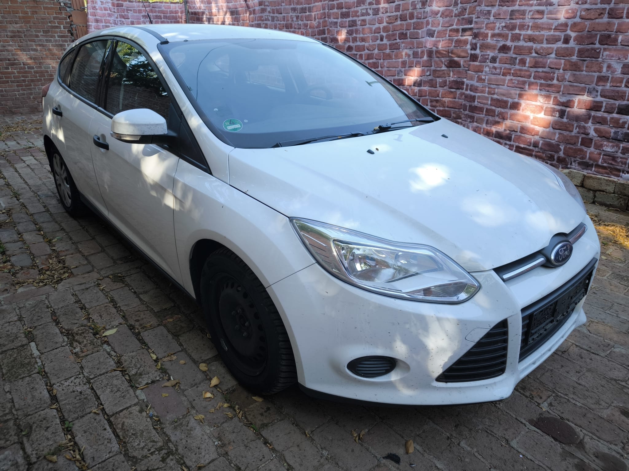 Weißer Ford Focus Gebrauchtwagen nach erfolgreichem Autoankauf in Minden auf Hof vor Backsteinmauer