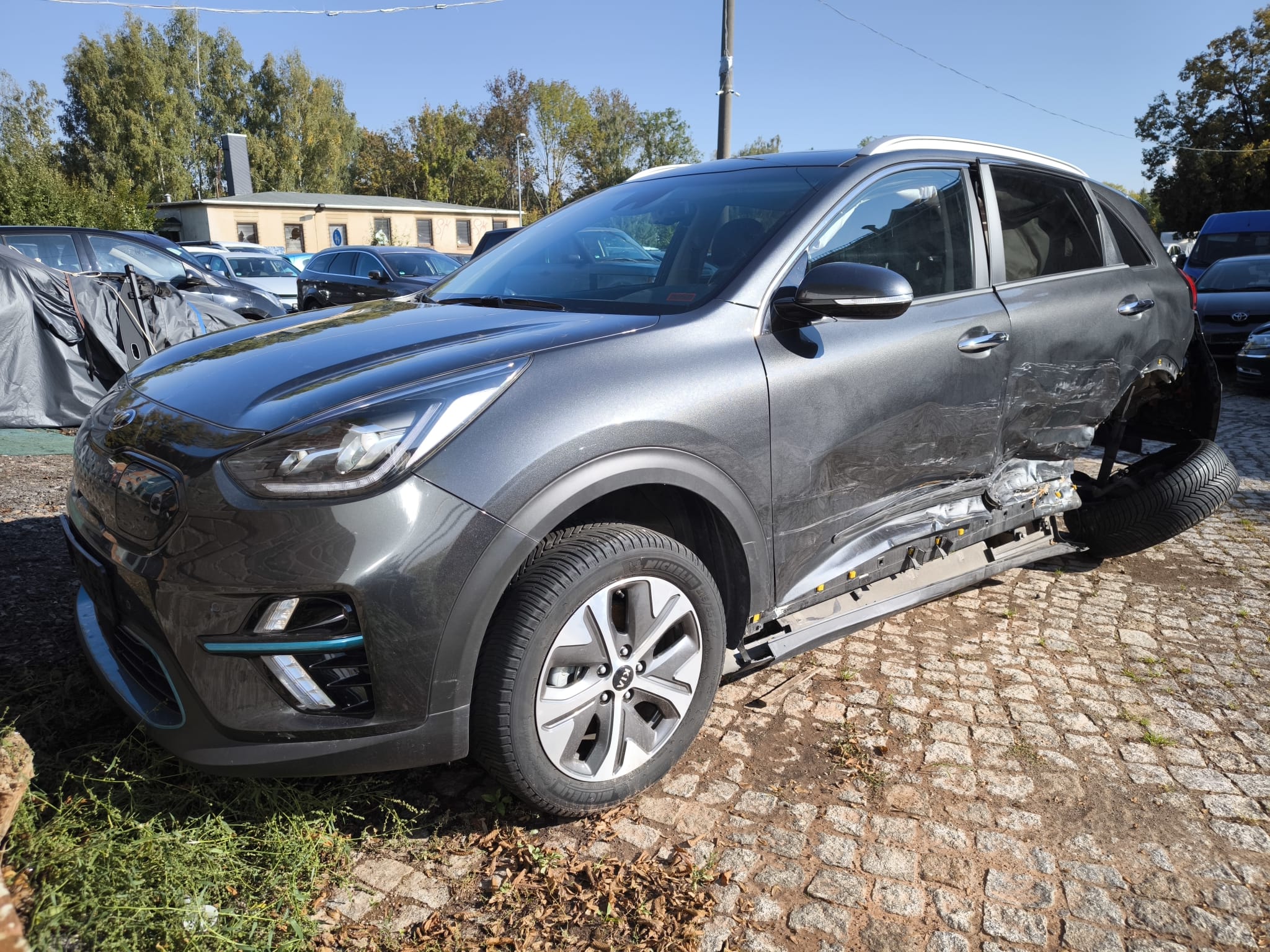 Schwer beschädigter Kia e-Niro mit Seitenschaden nach Unfall auf Hof in Neumünster zum Verkaufen als Unfallauto