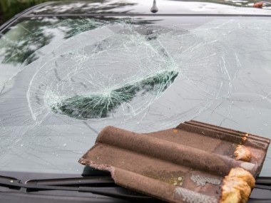 Auto mit Sturmschaden durch Dachziegel auf der Scheibe