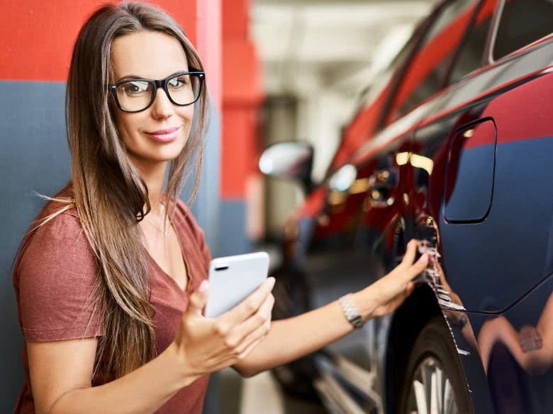 Frau meldet Parkschaden der Versicherung am Handy
