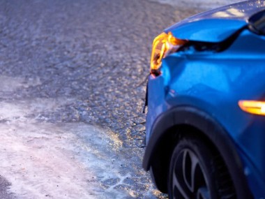 Auto mit Frontschaden und Warnblinker nach Glatteis-Unfall