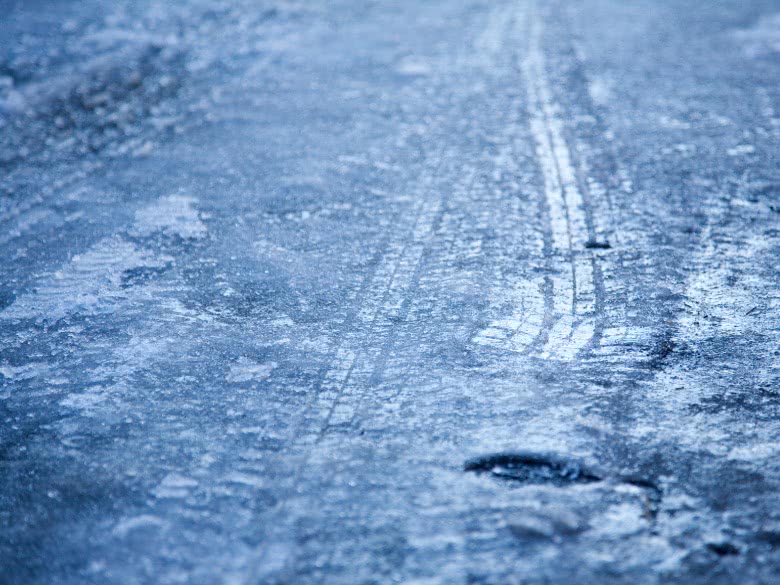 Glatt-Eis auf der Straße mit Reifenspuren