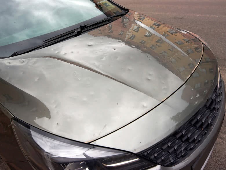 Auto mit Hagelschaden auf der Motorhaube infolge eines Unwetters