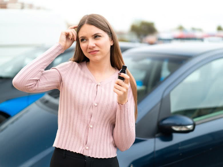 Frau frägt sich wann das Auto noch verkehrssicher ist mit Schlüssel in der Hand