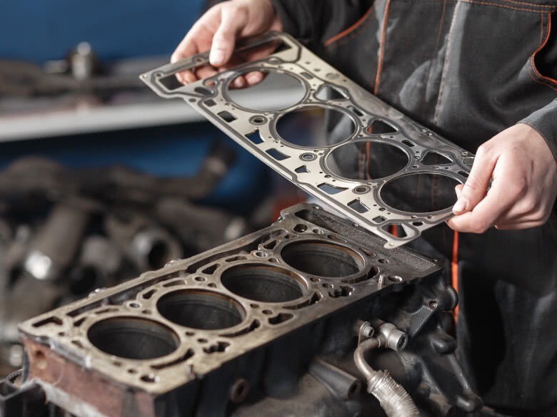 Zylinderkopfdichtung in der Hand am Motorblock