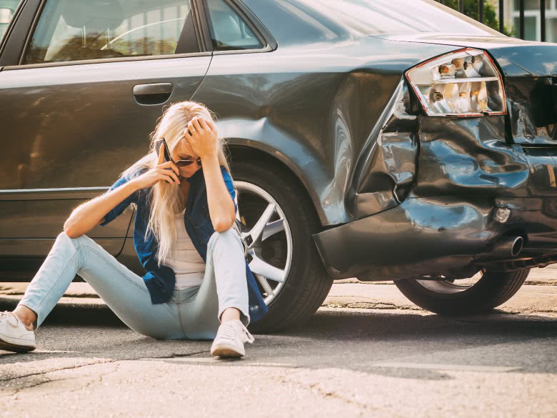 Frau sitzt verzweifelt am Unfallwagen