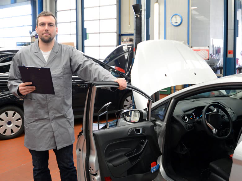 Ein Gutachter steht am eigenen Auto für das Gutachten