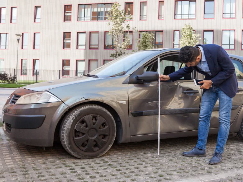 Gutachter misst das Schadensausmaß an der Seite des Autos