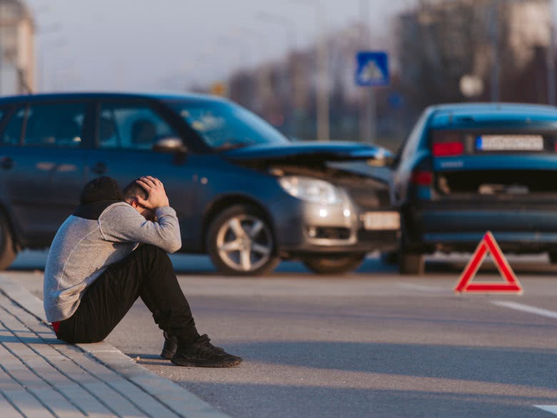 Mann ist am Verkehrsunfall beteiligt und sitzt am Straßenrand