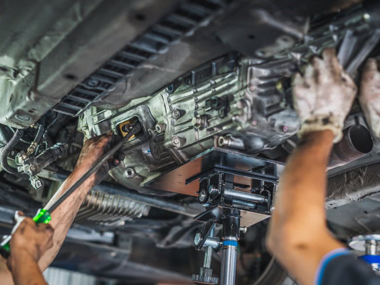 Mechaniker bauen das defekte Getriebe mit Getriebeschaden von unter dem Auto aus