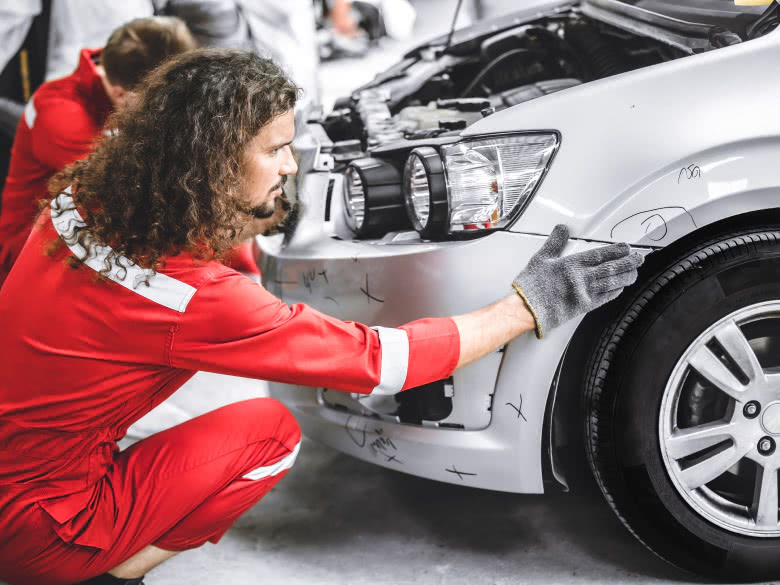 Mechaniker markiert Stellen des Frontschadens