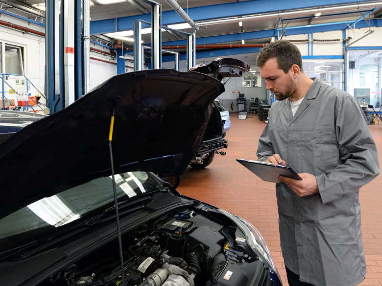 Gutachter betrachtet Motor im Auto beim Gutachten