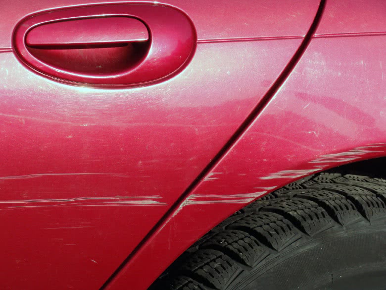 Rotes Auto mit Streifschaden an der hinteren Türe und dem Kotflügel
